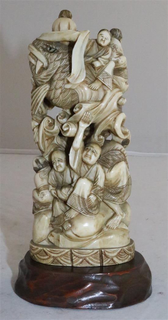 A Japanese walrus ivory okimono of men holding a giant carp, early 20th century, 15cm, wood stand